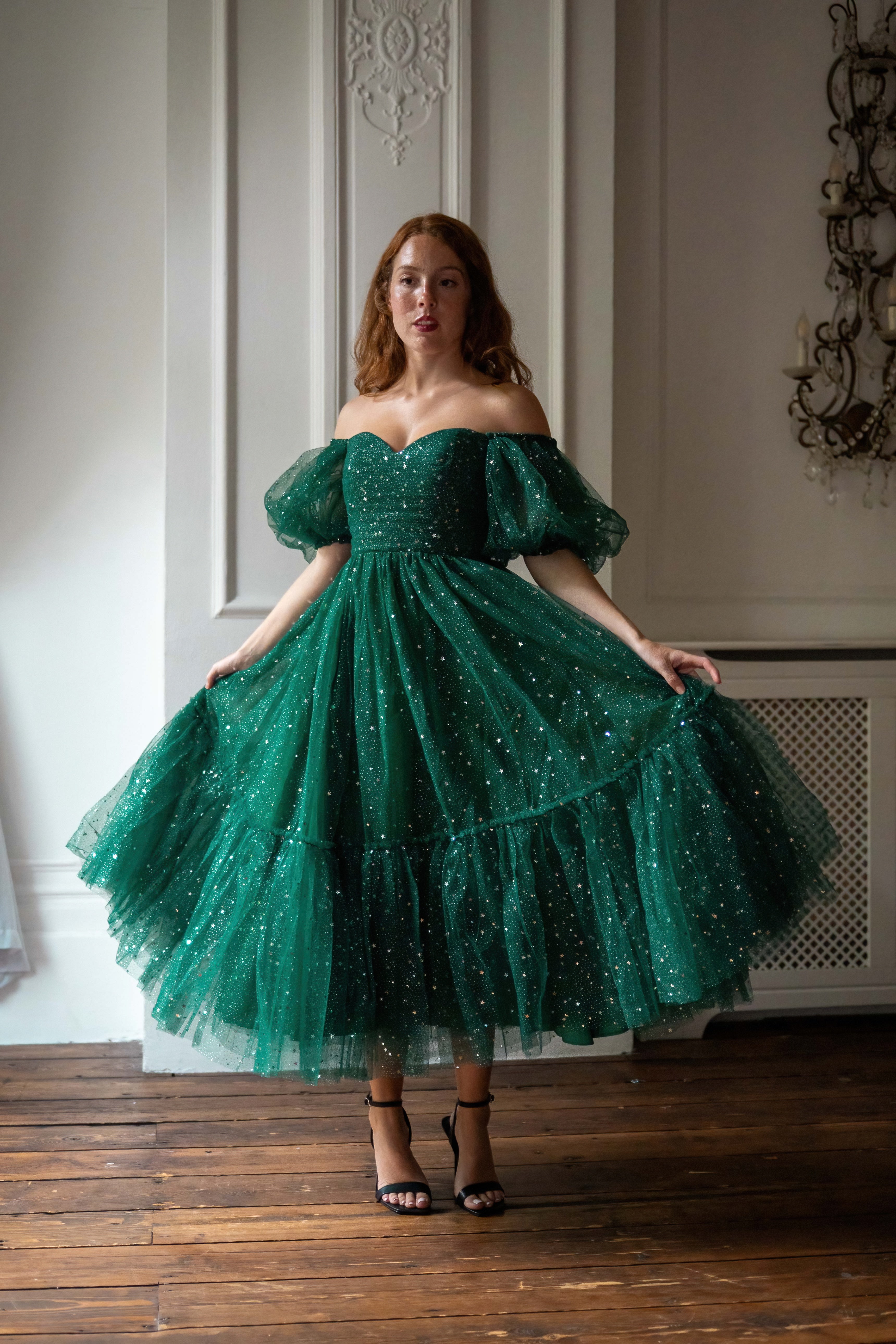 Woman wearing a green sparkly dress in an elegant room.