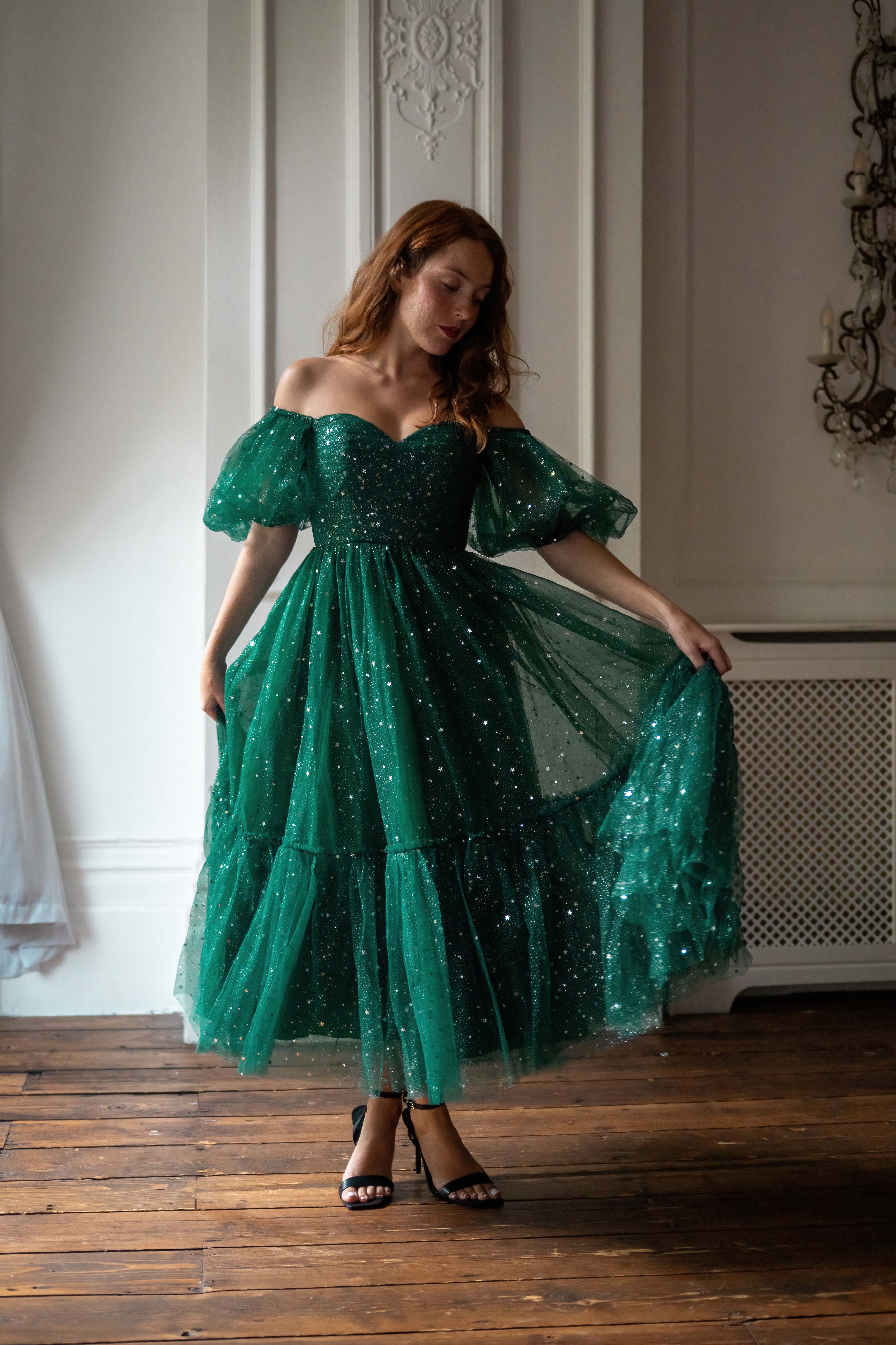 Woman wearing a green sparkly dress in an elegant room.